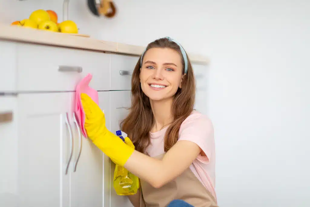 smiling woman wiping cabinets